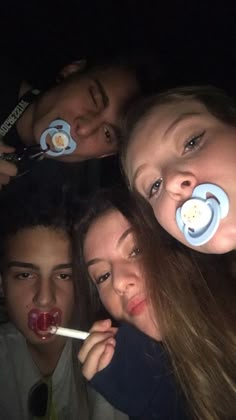 a group of young people with pacifiers on their mouths posing for the camera