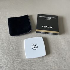 a white and black box sitting on top of a bed next to a small wallet