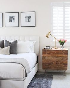 a bedroom with white walls and pictures on the wall above the bed, along with two nightstands