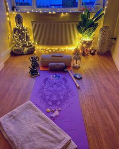 a yoga mat and towel on the floor in front of a window with fairy lights