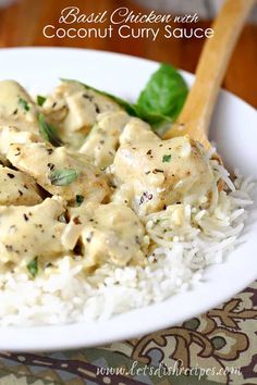 a white plate topped with rice and chicken covered in sauce next to a wooden spoon