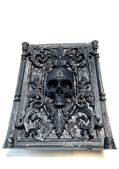 a skull is sitting in the middle of a decorative metal box with filigrees and scrolls