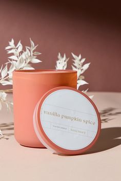 a pink candle sitting on top of a table next to some white flowers and leaves