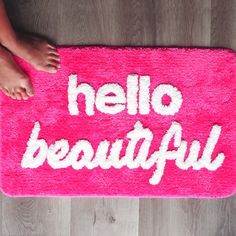 a pink rug with the words hello beautiful written on it and someone's feet