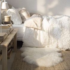 a bed with white blankets and pillows on top of it next to a wooden table