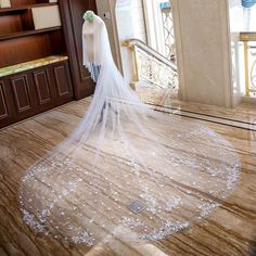 a bride's veil is draped over her wedding dress on the floor in front of stairs