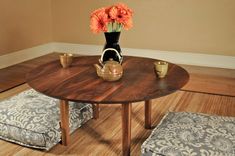 a vase with flowers sitting on top of a wooden table next to two stools