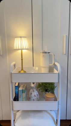 a white shelf with books and plants on it