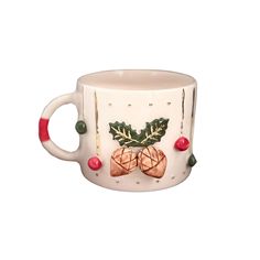 a ceramic mug with holly and bells on it