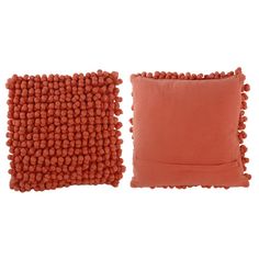 two orange pillows with pom - poms on the sides and one in red