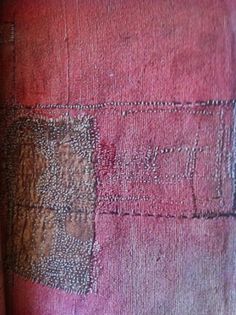 an old piece of cloth with some stitching on it and the fabric is red