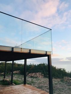 a wooden deck with glass railing on the top and ocean in the backgroud