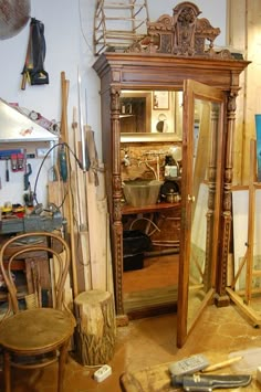 an old wooden armoire sitting inside of a room next to a chair and table