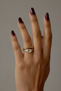 a woman's hand wearing a gold ring with a diamond on it and two other rings