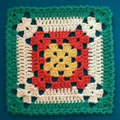 a crocheted square is shown on a blue surface with white, yellow and red accents