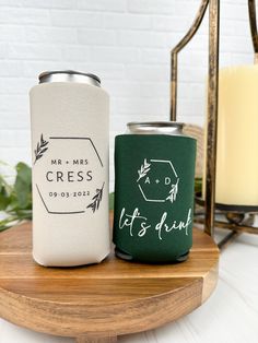 two can coolers sitting on top of a wooden table next to a lit candle