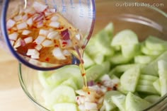 a person pouring dressing into a glass bowl filled with chopped onions and celery