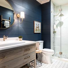 a white toilet sitting under a bathroom mirror next to a walk in shower and sink