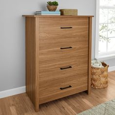 a wooden chest of drawers sitting on top of a hard wood floor next to a window