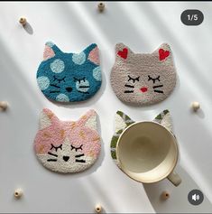 three cat shaped rugs sitting on top of a white table next to a cup