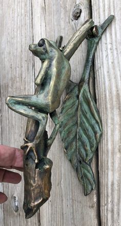 a bronze frog figurine hanging on a wooden wall