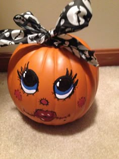 an orange pumpkin with eyes painted on it's face and a bow tied around the top