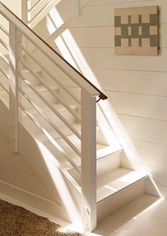 a white stair case next to a wooden wall