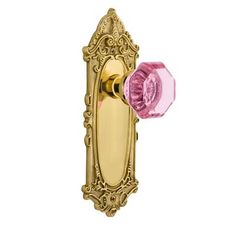 an ornate brass door handle with pink glass knob