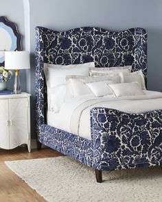 a blue and white bed in a bedroom next to a dresser with a mirror on it