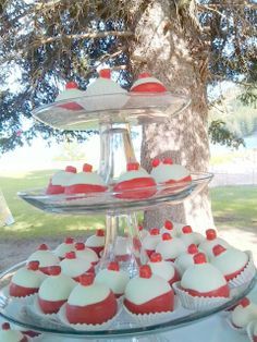 cupcakes are arranged on three tiered trays under a tree