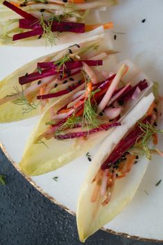 several different types of vegetables on a white plate with sprigs and seasoning