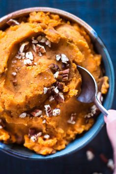 a bowl filled with mashed sweet potatoes topped with pecans