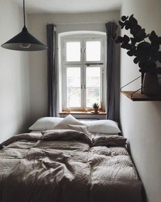 a bed sitting under a window next to a lamp