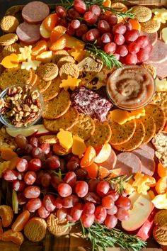 a platter filled with crackers, grapes, nuts and other foodstuffs