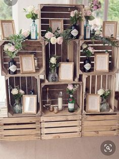 several wooden crates filled with flowers and framed pictures on top of each other in front of a window