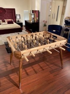 a wooden foosball sitting on top of a hard wood floor next to a bed