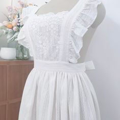 Size:From length: 39 inch, Hem length: 27 inch, Approximate bust: 33-35inch, Lacing length: 30 inch Vintage Style Design: This white cotton lace apron draws inspiration from vintage aesthetics, featuring a unique scallop edge design that adds a touch of fashion and elegance to your baking and housework activities. Adjustable Design: The apron comes with adjustable neck and waist straps to fit various body shapes, ensuring comfortable wear and allowing you to unleash your creativity in the kitchen. Durable Comfort: Crafted from high-quality cotton fabric and delicate lace, it offers superior durability and a soft touch, making it an ideal choice for both cooking and household chores. Belle Fancy Dress, Unique Aprons, Vintage Style Aprons, Apron Vintage, Lace Apron, Embroidered Apron, White Apron, Scallop Edge, Aprons Vintage