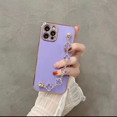 a woman is holding up her phone case with an attached chain and ring on it