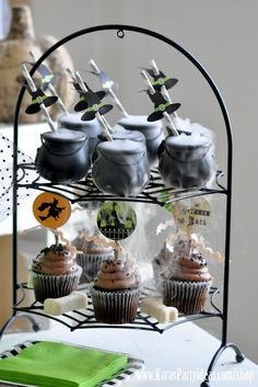 cupcakes are arranged on a black stand with green napkins and halloween decorations