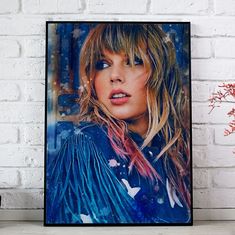 a framed photograph of a woman's face on a white brick wall