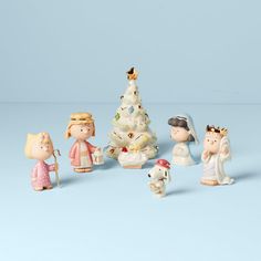 a group of small figurines standing next to a christmas tree