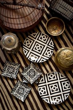 several pieces of pottery sitting on top of a striped table cloth next to a vase