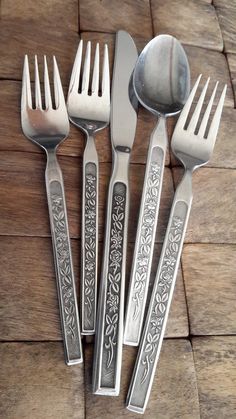 five forks and two spoons on a wooden table