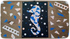 a seahorse is surrounded by confetti and blue triangles on a wooden surface