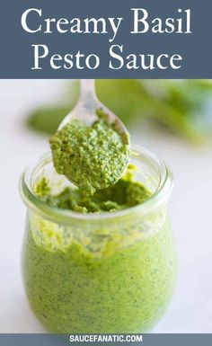 a spoon full of creamy basil pest on top of a jar filled with pesto