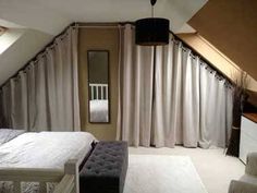 an attic bedroom with beige curtains and white bedding