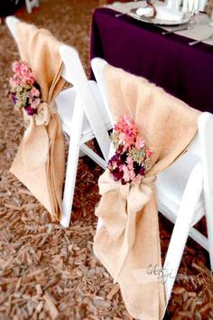 two white folding chairs covered in burlap and pink flowers with bows tied to them