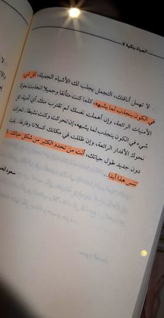 an open book with arabic writing on the pages and orange highlighters in each corner