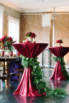 the tables are decorated with red cloths and greenery for an elegant wedding reception