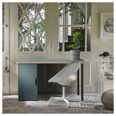 an office desk with a chair and potted plant in front of the mirror on the wall